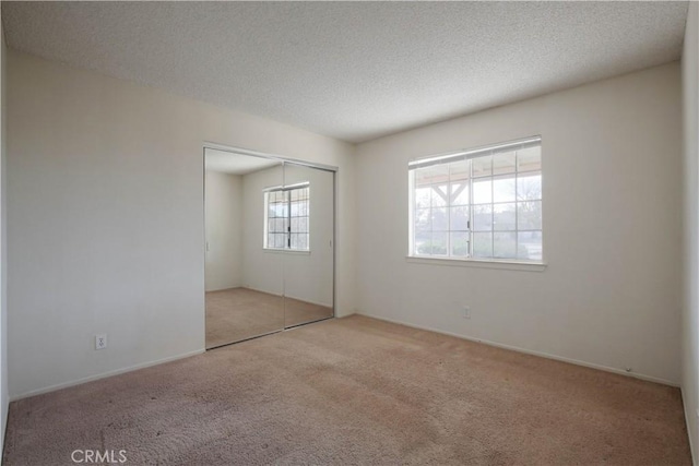 unfurnished bedroom with light carpet, a closet, and a textured ceiling