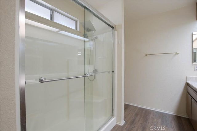 bathroom featuring hardwood / wood-style floors, a shower with door, and vanity