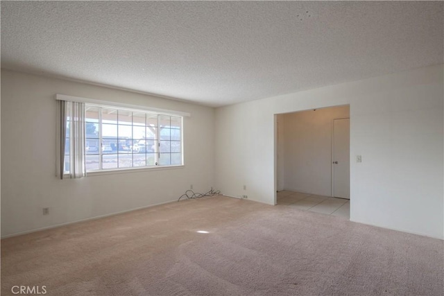 empty room with a textured ceiling and light carpet