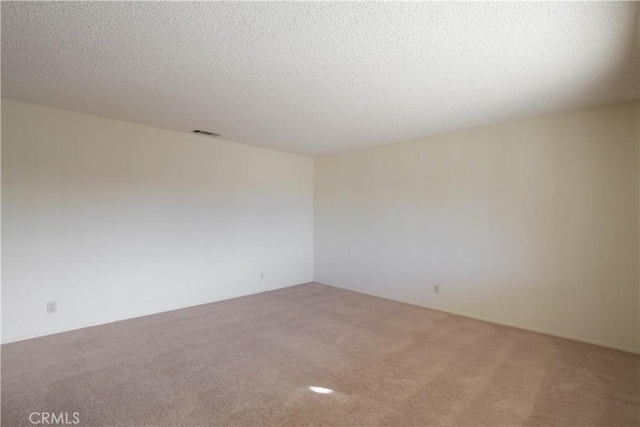 carpeted spare room with a textured ceiling