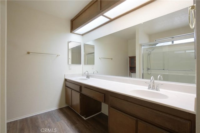 bathroom featuring a shower with shower door, hardwood / wood-style flooring, and vanity