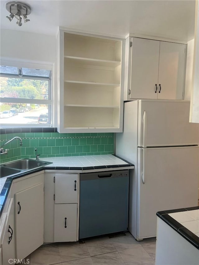 kitchen featuring sink, white cabinetry, black dishwasher, and tile countertops