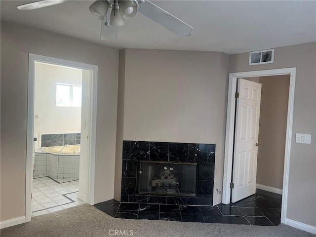 unfurnished living room featuring ceiling fan, dark carpet, and a tiled fireplace