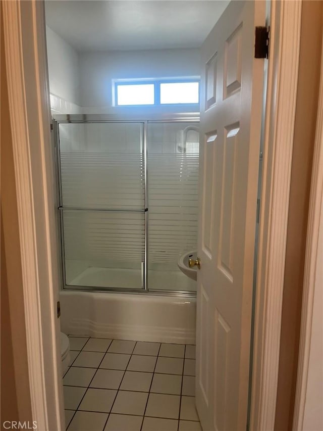 bathroom with bath / shower combo with glass door, toilet, and tile patterned flooring