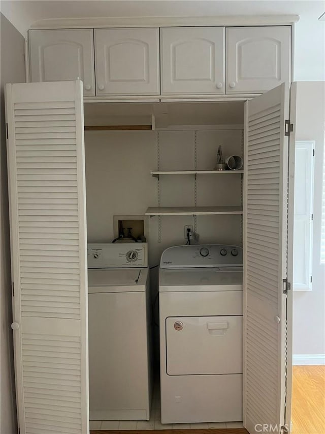 laundry area with cabinets, light wood-type flooring, and washing machine and clothes dryer