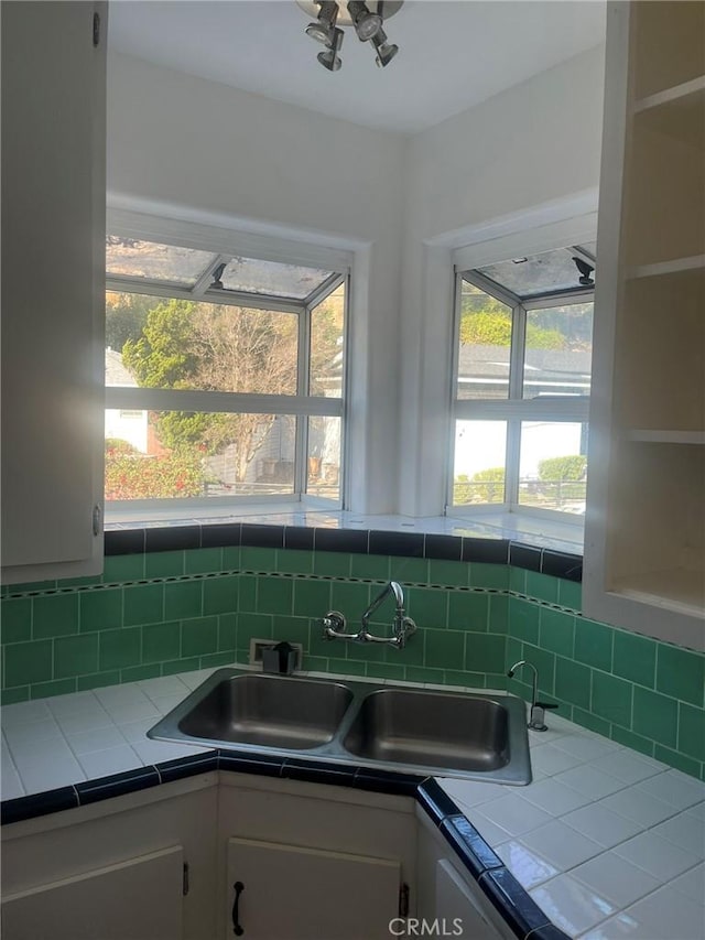 kitchen with plenty of natural light, sink, white cabinetry, and tile counters