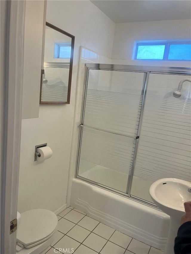 bathroom with combined bath / shower with glass door, tile patterned floors, and toilet