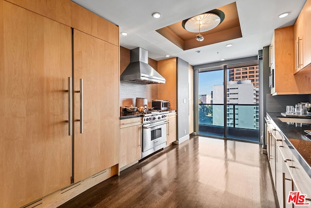 kitchen featuring high end stainless steel range, dark stone countertops, ventilation hood, and tasteful backsplash