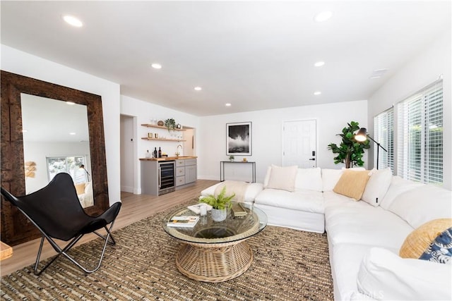 living room with indoor bar, beverage cooler, and light hardwood / wood-style floors