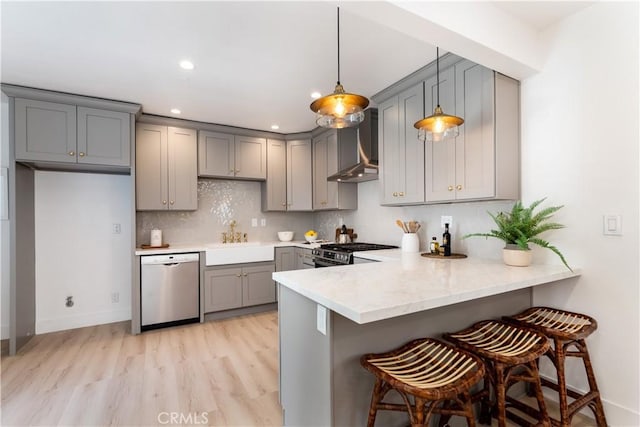 kitchen with appliances with stainless steel finishes, gray cabinets, kitchen peninsula, and hanging light fixtures