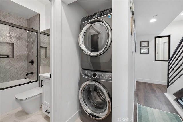 washroom with stacked washing maching and dryer and wood-type flooring