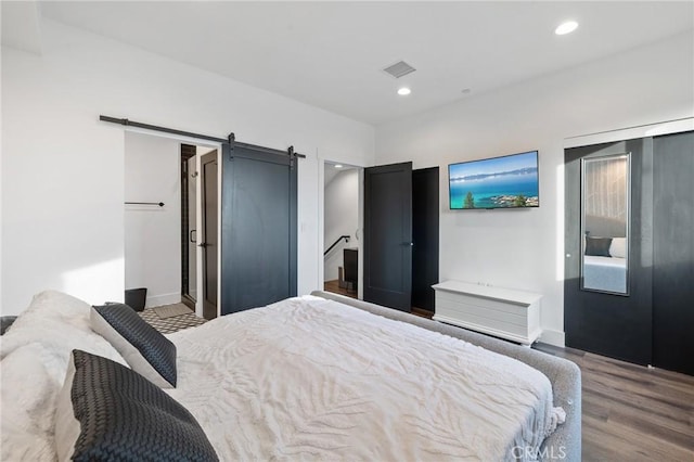 bedroom with hardwood / wood-style flooring and a barn door