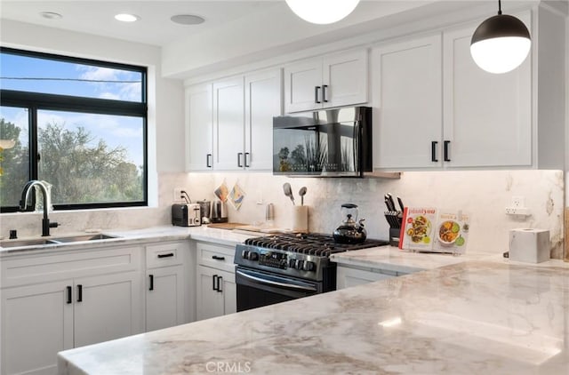 kitchen featuring stainless steel appliances, white cabinets, decorative light fixtures, and sink