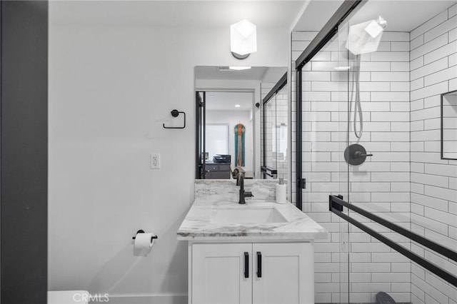 bathroom featuring a shower with shower door and vanity