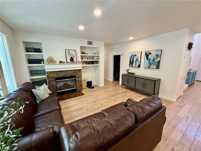 living room featuring a fireplace, built in features, and light hardwood / wood-style floors