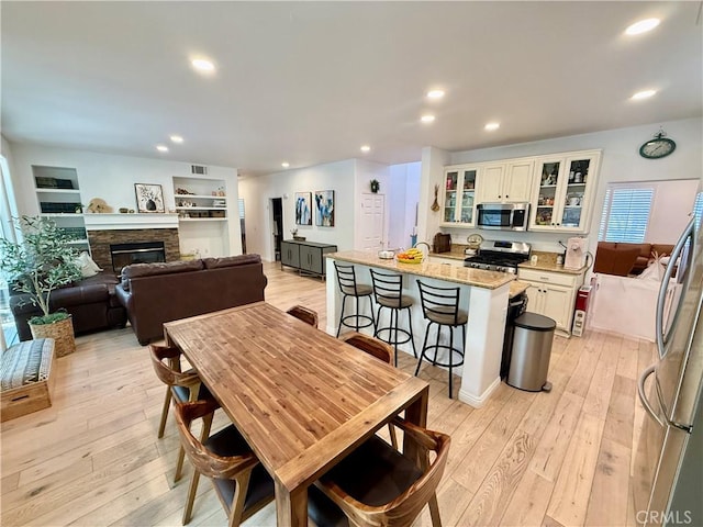 dining space featuring light wood-type flooring and a stone fireplace