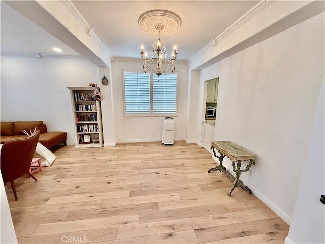 living area featuring a chandelier, crown molding, and light hardwood / wood-style floors