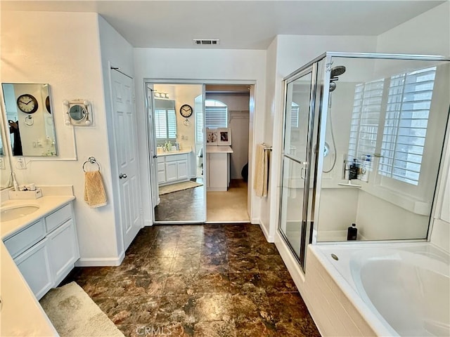 bathroom with vanity and shower with separate bathtub