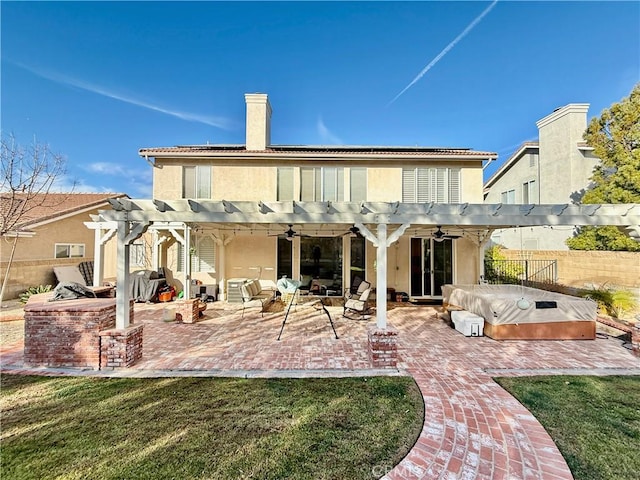 back of property with a pergola, an outdoor hot tub, a lawn, and a patio