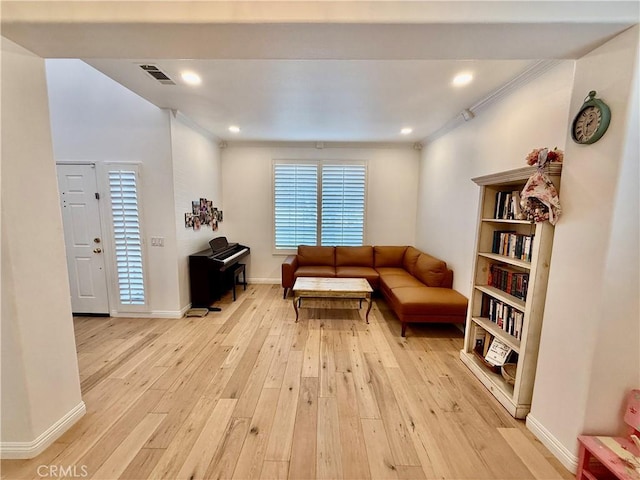 living room with ornamental molding and light hardwood / wood-style floors