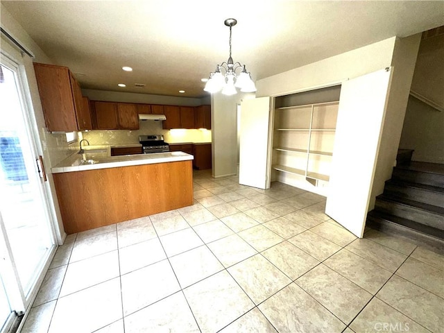 kitchen with a chandelier, hanging light fixtures, decorative backsplash, stainless steel range with electric stovetop, and kitchen peninsula