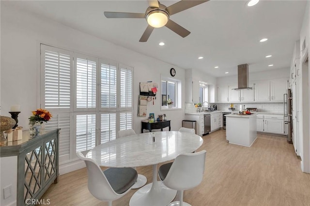 dining room featuring ceiling fan, a wealth of natural light, light wood-type flooring, and sink