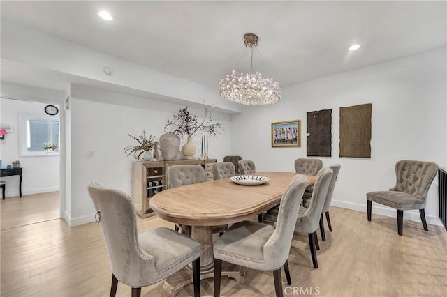 dining space with light wood-type flooring and an inviting chandelier