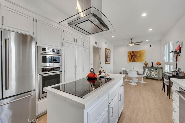 kitchen with light hardwood / wood-style floors, ceiling fan, appliances with stainless steel finishes, white cabinets, and a center island