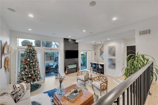 living room with light hardwood / wood-style floors, a fireplace, and a healthy amount of sunlight