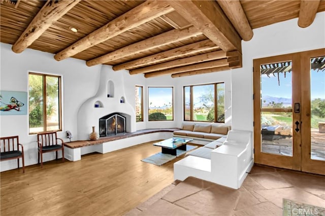 living room with french doors, plenty of natural light, beamed ceiling, and wooden ceiling