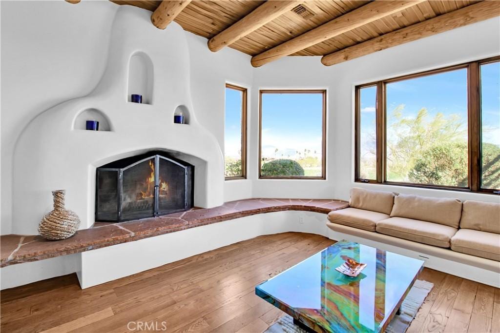 unfurnished living room with hardwood / wood-style floors, beam ceiling, and wood ceiling