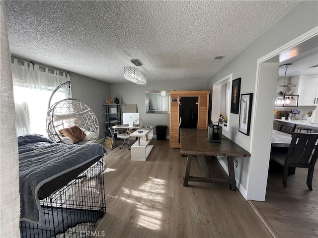 bedroom with a textured ceiling and light hardwood / wood-style flooring