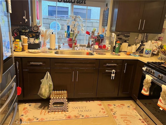 kitchen with stainless steel gas stove, dark brown cabinetry, and sink