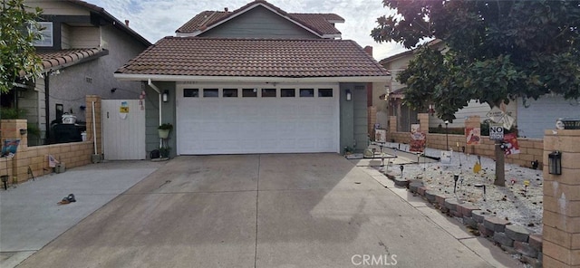 view of front of home featuring a tile roof, concrete driveway, and a garage