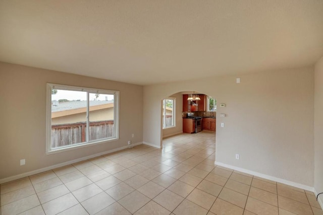 spare room featuring plenty of natural light, light tile patterned flooring, and a chandelier