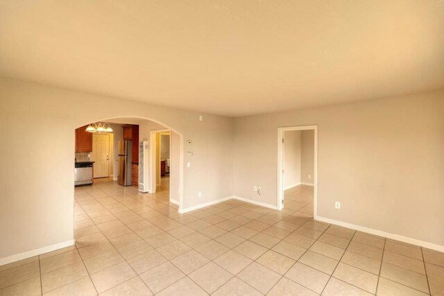 tiled empty room with an inviting chandelier