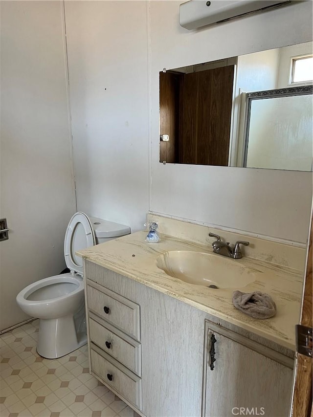 bathroom with toilet, an AC wall unit, a shower with shower door, and vanity