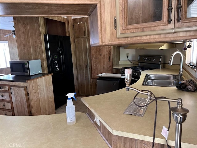 kitchen featuring ceiling fan, sink, wooden walls, and black appliances