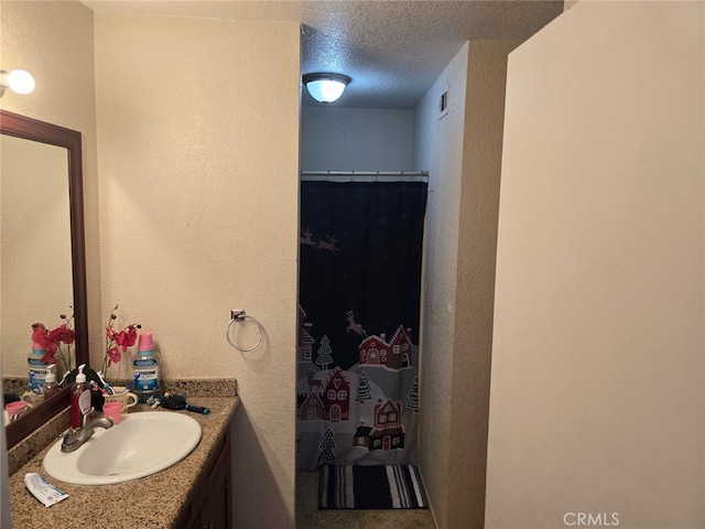 full bath with a textured ceiling, a textured wall, vanity, and a shower with curtain