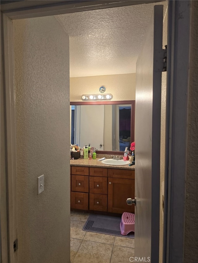 bathroom with a textured ceiling, a textured wall, vanity, and tile patterned floors