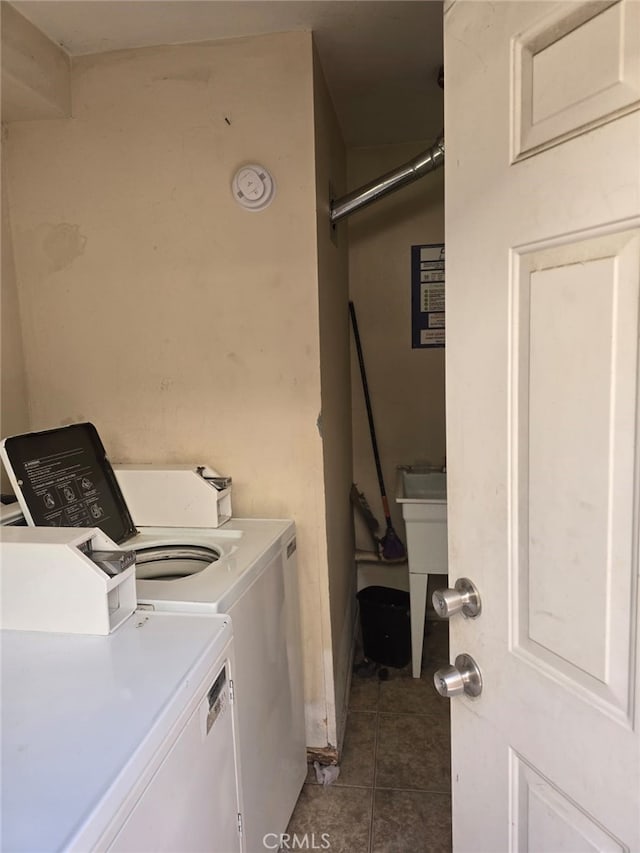 clothes washing area featuring tile patterned flooring, laundry area, a sink, and washer and clothes dryer