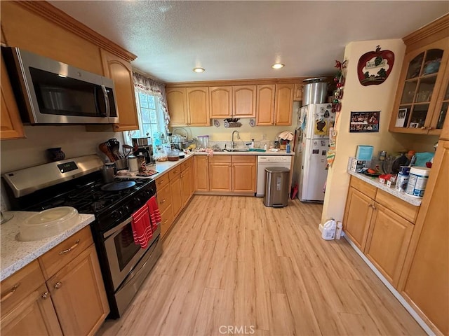 kitchen featuring light stone countertops, sink, stainless steel appliances, and light hardwood / wood-style flooring