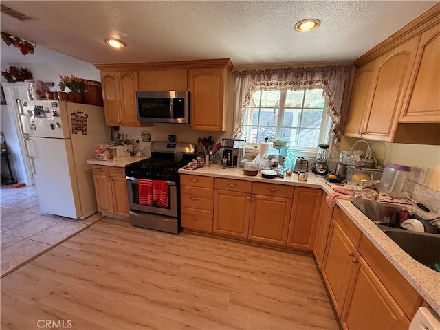 kitchen featuring light hardwood / wood-style floors, a textured ceiling, and appliances with stainless steel finishes