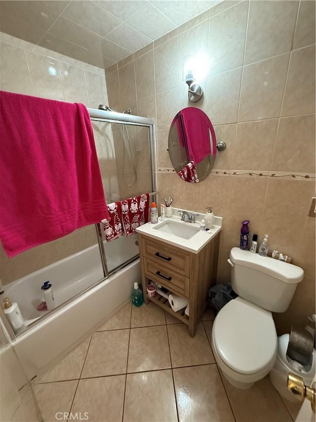 full bathroom with toilet, vanity, tile walls, tile patterned floors, and enclosed tub / shower combo