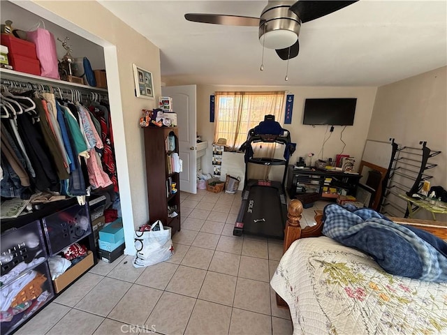 tiled bedroom with ceiling fan and a closet