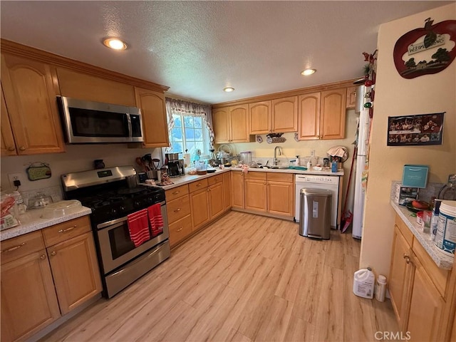 kitchen with light hardwood / wood-style floors, sink, a textured ceiling, stainless steel appliances, and light stone counters