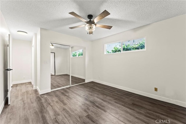 unfurnished bedroom with ceiling fan, a closet, dark hardwood / wood-style floors, and a textured ceiling