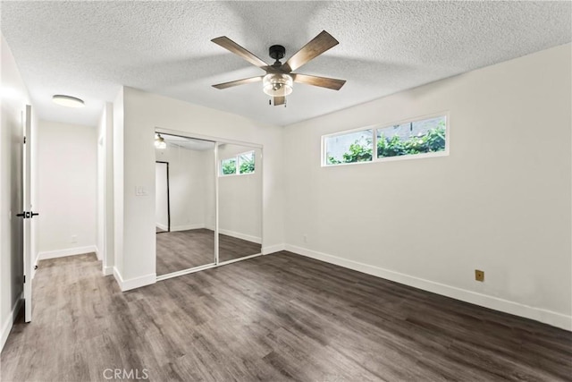 unfurnished bedroom with dark wood-type flooring, ceiling fan, a closet, and a textured ceiling