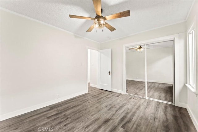 unfurnished bedroom with a textured ceiling, ceiling fan, dark hardwood / wood-style flooring, and a closet