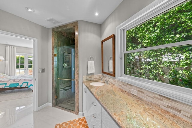 bathroom with tile patterned flooring, walk in shower, tasteful backsplash, and vanity